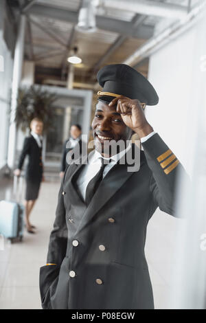 Young Pilot im Flughafen an Kamera Stockfoto