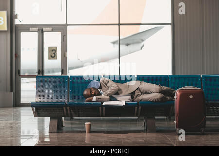 Erschöpft, Geschäftsmann, schlafen auf den Sitzen beim Warten auf der Reise am Flughafen Lobby Stockfoto