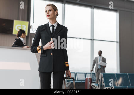 Pilotin mit Koffer am Flughafen Empfang Stockfoto