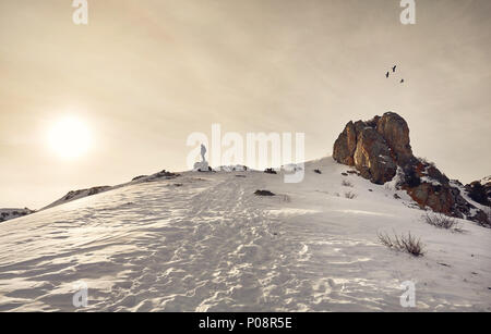 Wanderer auf dem Rock mit Trekking genießen Sie den Blick auf die schneebedeckten Berge an dramatischer Sonnenaufgang Himmel. Stockfoto