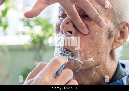 Älterer Mann seinen Bart abrasiert bekommen von jungen qualifizierten Mann zu Hause Stockfoto