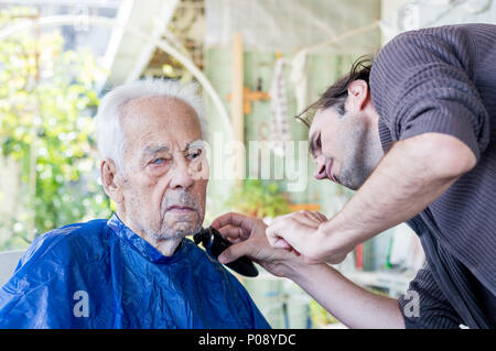 Älterer Mann seinen Bart abrasiert bekommen von jungen qualifizierten Mann zu Hause Stockfoto