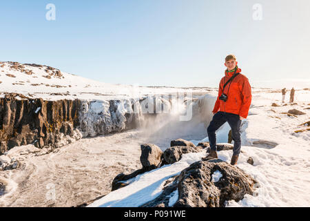 Mann mit Kamera stehen am Rand, Selfoss Wasserfall im Winter, Gorge, Northern Island, Island Stockfoto