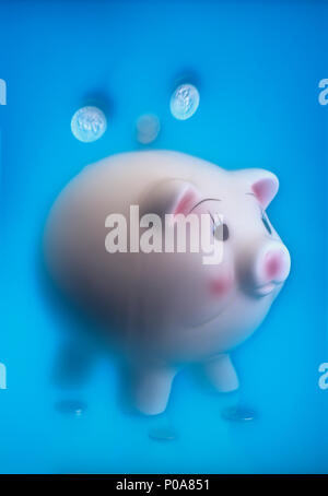 Konzeptionelle Bild von Münzen, die vom Himmel fallen in ein Sparschwein mit einem weichen ätherischen Hintergrund Stockfoto