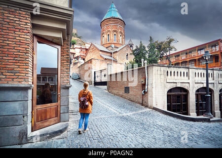 Touristische Frau in braunen Sakko Spaziergang durch die alten Straßen in der Nähe der Kirche im Zentrum von Tiflis, Georgien