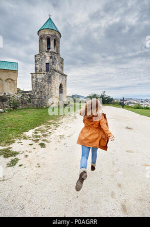 Frau zu laufen, um die Kapelle Turm von bagrati Kirche bei bedecktem Himmel in Kutaissi, Georgien Stockfoto