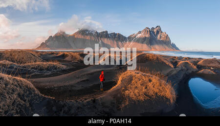 Abendstimmung am langen lavastrand, man zwischen dem schwarzen Sand Dünen mit trockenem Gras bedeckt, Berge Klifatindur Stockfoto