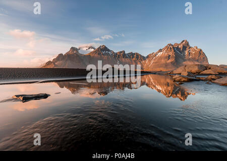 Abendstimmung am langen lavastrand, schwarzer Sandstrand, der Reflexion im Wasser, in den Bergen Klifatindur Stockfoto