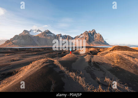 Abendstimmung am langen lavastrand, man zwischen dem schwarzen Sand Dünen mit trockenem Gras bedeckt, Berge Klifatindur Stockfoto