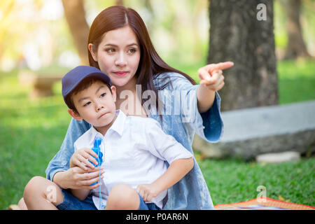 Schöne asiatische Mutter spielt mit ihrer schönen Sohn Hand zeigen auf der Suche Zukunft Konzept. Stockfoto