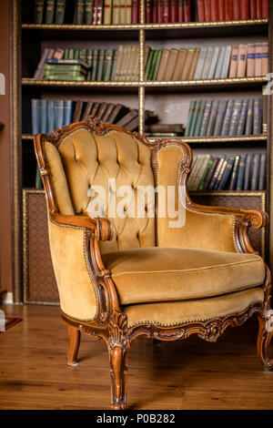 Bücher über Bücherregale. Luxus gelb Sessel in Bibliothek. Still Life Vintage Stuhl. Alte vintage Möbeln, beige Sessel Stockfoto