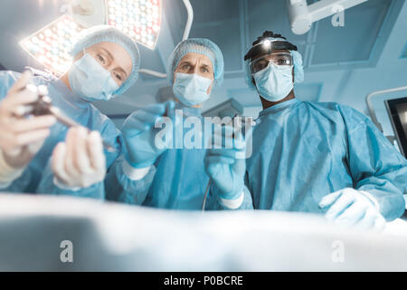 Ansicht von unten auf das multikulturelle Chirurgen bei Patienten, die während der Operation Stockfoto