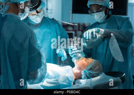 Afrikanische amerikanische Anästhesist holding Sauerstoffmaske Patient in der Chirurgie Zimmer Stockfoto