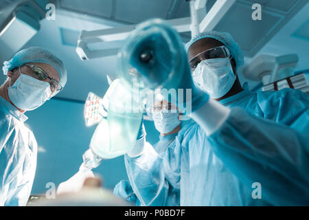 Ansicht von unten auf das afrikanische amerikanische Anästhesist holding Sauerstoffmaske patient Stockfoto