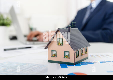 Haus Modell auf dem Schreibtisch, Hypothek, Investitionen oder Haus gebäude Konzept. Immobilienmakler bei der Arbeit. Stockfoto