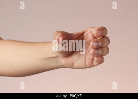 Hand, die Flasche. Geste der Hand halten Flasche auf braunem Hintergrund isoliert Stockfoto