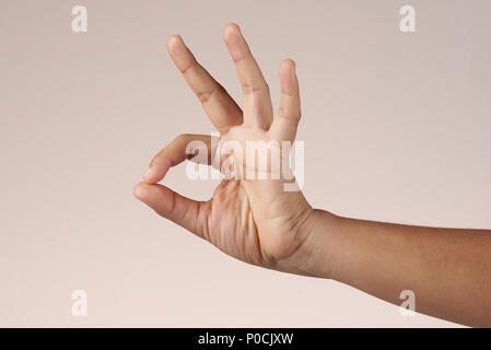 Hand zeigen ok Zeichen auf braunem Hintergrund isoliert Stockfoto