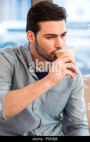 Porträt der jungen gutaussehenden Mann trinken Eis Kaffee im Cafe Stockfoto