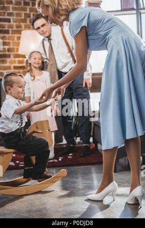 Happy 50s style Familie an der niedlichen kleinen Jungen auf Schaukelpferd zu Hause sitzen auf der Suche Stockfoto