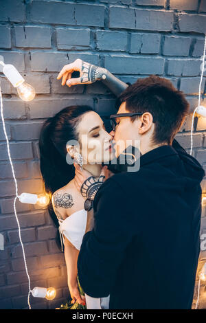 Junge Braut und Bräutigam Umarmen und Küssen unter grauen Mauer Stockfoto