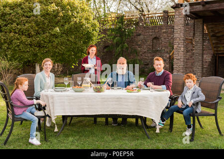 Große, glückliche Familie beim Abendessen zusammen an der Landschaft Stockfoto