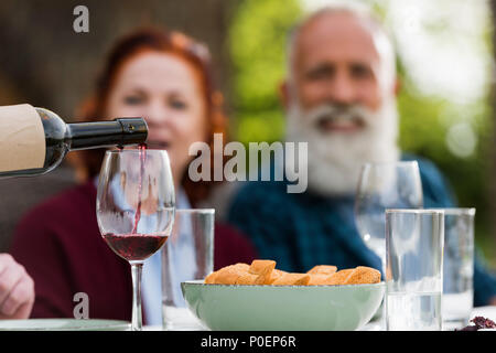 Selektiver Fokus der senior Paar in Gießen Rotwein in Glas Prozess suchen Stockfoto