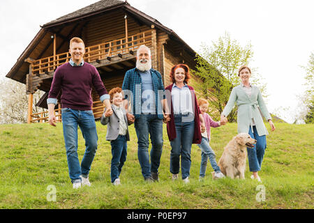 Glückliche Familie Hand in Hand zusammen, während in der Nähe von Country Haus im Dorf Stockfoto