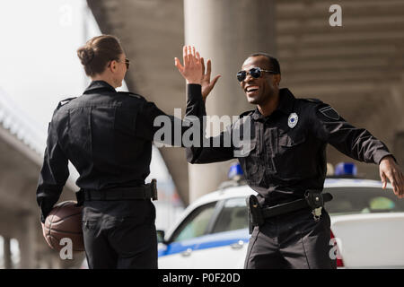 Polizisten mit Basketball Ball hoch fünf Stockfoto