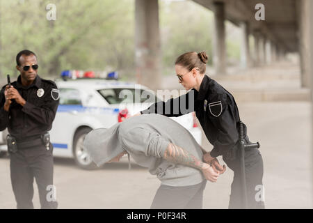 Die Offiziere der Polizei verhaften männliche Kriminelle in Hoodie Stockfoto