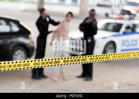 Closeup Schuß von Cross Line und Polizisten verhaften Frau auf unscharfen Hintergrund Stockfoto