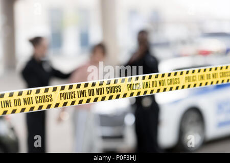 Detailansicht der Cross Line und Polizisten verhaften Frau auf unscharfen Hintergrund Stockfoto