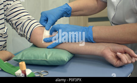 Krankenschwester, Pflaster auf weibliche Arm nach Blutspende Stockfoto