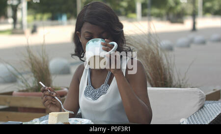 Portrait der junge schwarze Frau Essen im Café im Freien Stockfoto