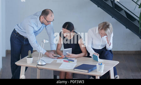 Gruppe junger Geschäftsleute arbeiten und miteinander kommunizieren in kreative Büros über verschiedene Geräte Stockfoto