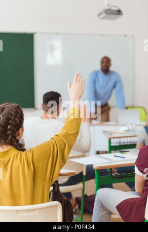 Ansicht der Rückseite des Schulmädchen mit Arm mit Klassenkameraden und Lehrer im Klassenzimmer Stockfoto