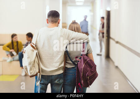 Rückansicht der jugendlichen Schüler Paar von der Schule gang und umarmt Stockfoto