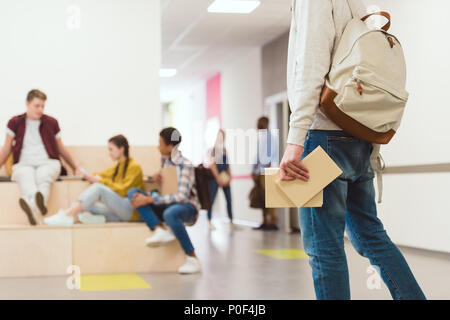 7/8 Schuß von Student mit Rucksack und Bücher stehen in der Schule Korridor Stockfoto