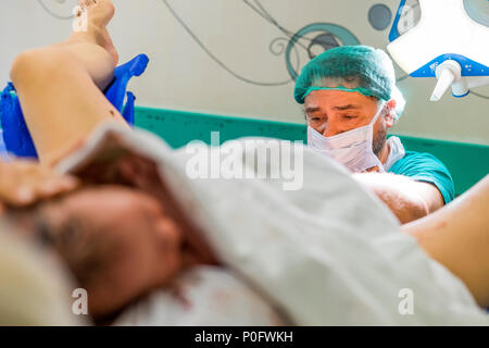 Faro, Portugal - Mai 7, 2018: Der Arzt und niedlichen neugeborenen Baby gleich nach der Geburt im Vordergrund. Stockfoto