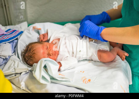 Erste Dressing up der neugeborenen Baby boy von Krankenschwester durchgeführt Stockfoto