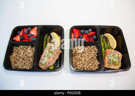Geplante Mahlzeiten in den Behältern - Lachs mit Spargel, Quinoa und frisches Obst. Stockfoto