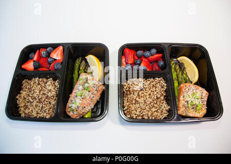 Geplante Mahlzeiten in den Behältern - Lachs mit Spargel, Quinoa und frisches Obst. Stockfoto