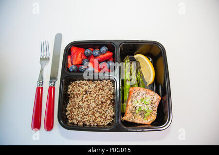 Geplante Mahlzeiten in den Behältern - Lachs mit Spargel, Quinoa und frisches Obst. Stockfoto