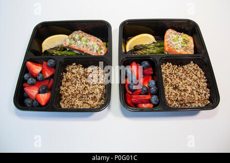 Geplante Mahlzeiten in den Behältern - Lachs mit Spargel, Quinoa und frisches Obst. Stockfoto