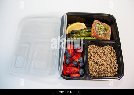 Geplante Mahlzeiten in den Behältern - Lachs mit Spargel, Quinoa und frisches Obst. Stockfoto