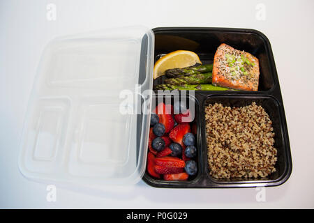 Geplante Mahlzeiten in den Behältern - Lachs mit Spargel, Quinoa und frisches Obst. Stockfoto