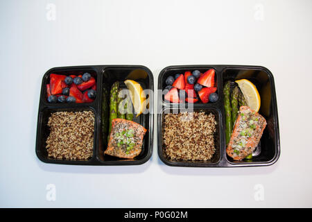 Geplante Mahlzeiten in den Behältern - Lachs mit Spargel, Quinoa und frisches Obst. Stockfoto