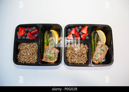 Geplante Mahlzeiten in den Behältern - Lachs mit Spargel, Quinoa und frisches Obst. Stockfoto