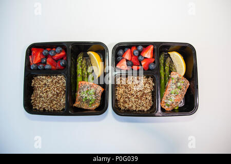 Geplante Mahlzeiten in den Behältern - Lachs mit Spargel, Quinoa und frisches Obst. Stockfoto