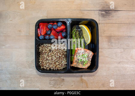 Geplante Mahlzeiten in den Behältern - Lachs mit Spargel, Quinoa und frisches Obst. Stockfoto
