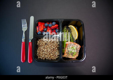Geplante Mahlzeiten in den Behältern - Lachs mit Spargel, Quinoa und frisches Obst. Stockfoto